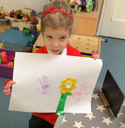 Reception child holding up their plant picture drawing