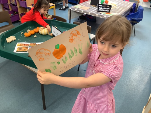 Reception child with a Harvest Festival painting