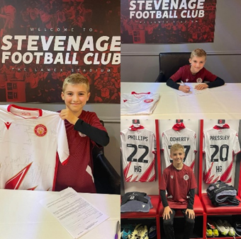 Dylan signing his contract and holding up his Stevenage football shirt